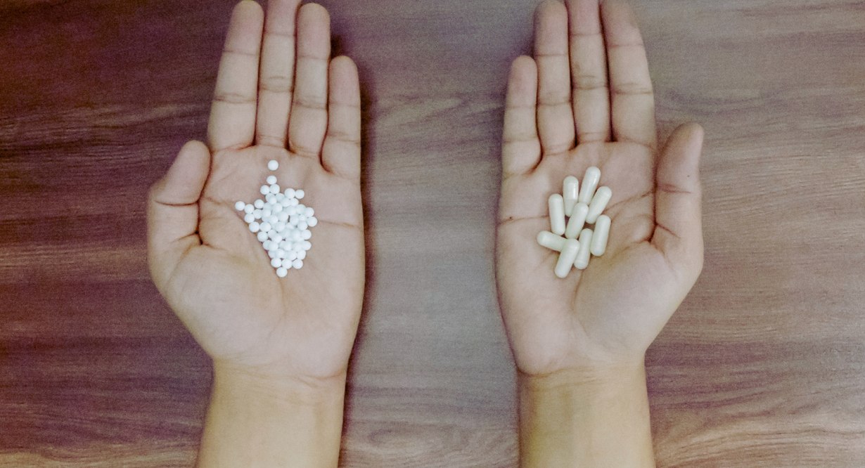 Mains ouvertes comparant globules homéopathiques et gélules allopathiques, médecine alternative